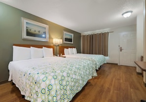 Habitación de hotel con dos camas, una mesita de noche, una lámpara, una puerta y dos cuadros en la pared.