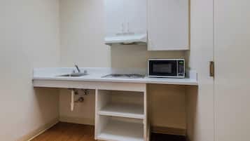 A compact kitchenette with a microwave, stove, and sink.