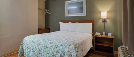 Una camera d'albergo con un letto, un comodino, una lampada e un quadro appeso al muro.