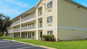 A multi-story hotel with a flat roof, balconies, and a parking lot. - HomeTowne Studios by Red Roof Orlando - UCF Area (Orlando)