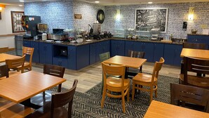 A restaurant with blue cabinets, wooden tables, and chairs. - AmericInn by Wyndham Chanhassen (Chanhassen)