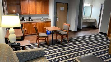 A compact living space with a kitchenette, a dining area with a table and chairs, and a seating area with a sofa and a lamp.