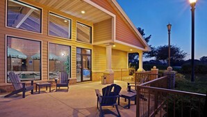 A building with large windows, outdoor seating, and a well-lit entrance. - AmericInn by Wyndham Chanhassen (Chanhassen)