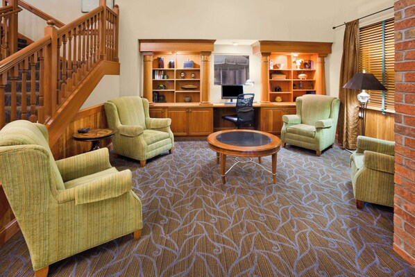 A cozy living room with a patterned carpet, wooden furniture, and a staircase.