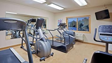 Un gimnasio con cintas de correr, elípticas y una bicicleta estática.