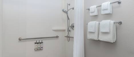 Un espace douche doté d’une porte en verre, d’un sèche-mains et d’un porte-serviettes avec des serviettes.