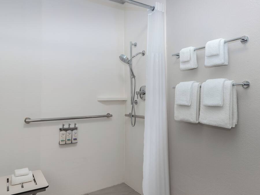 A shower area with a glass door, a hand dryer, and a towel rack with towels.
