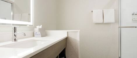Une salle de bain moderne avec un grand miroir, un lavabo et un espace douche.