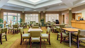 A hotel dining area with tables and chairs, a reception desk, and large windows with blinds. - La Quinta Inn & Suites by Wyndham Fremont / Silicon Valley (Fremont)
