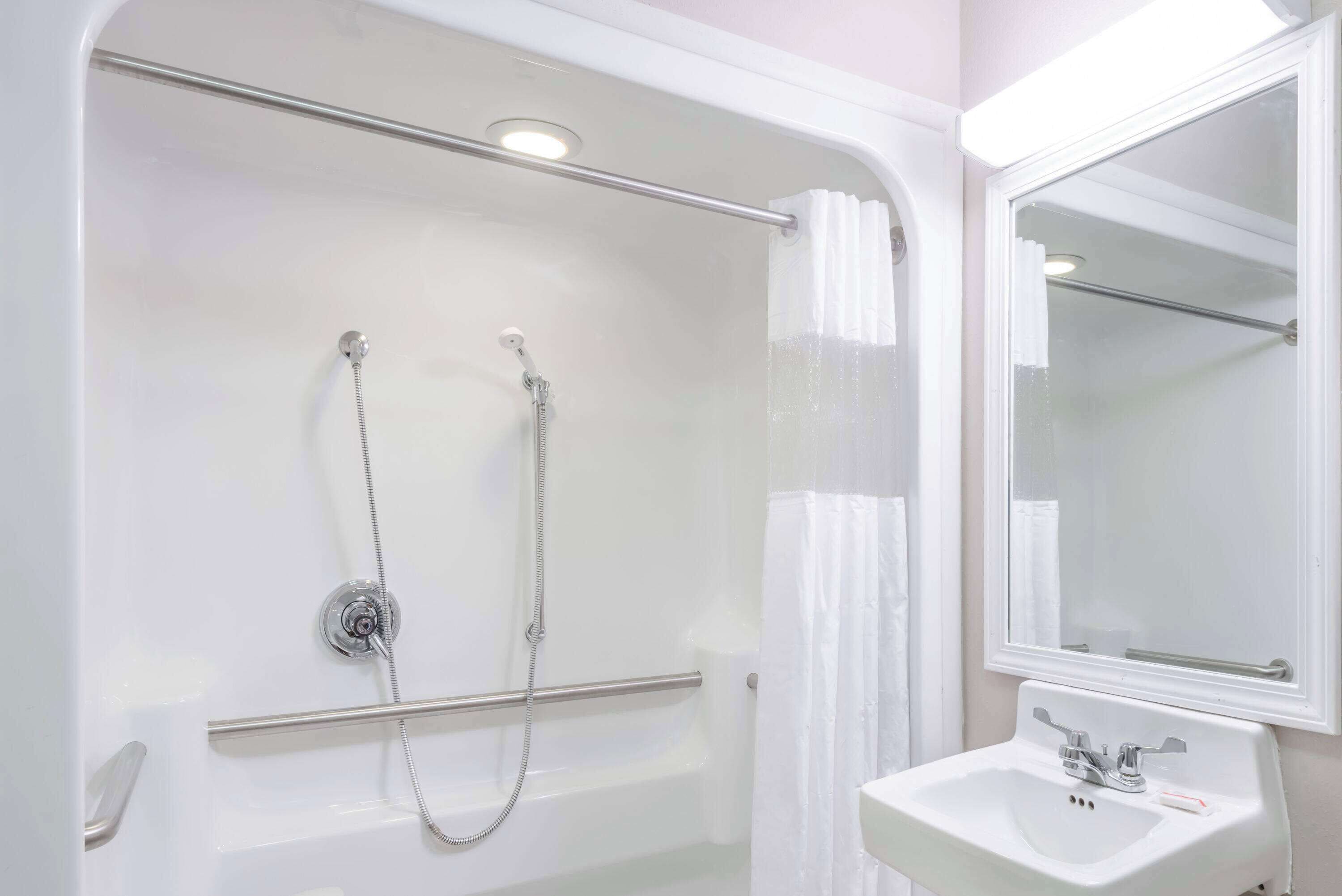A modern bathroom with a walk-in shower, a glass-enclosed toilet, and a white sink with a mirror.