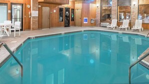 Zona de piscina con piso de baldosas, una silla de salvavidas y un cartel que indica una profundidad de 9 pies.
