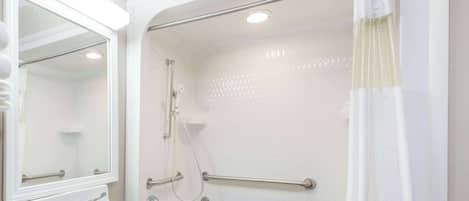 Un baño con lavamanos blanco, espejo y zona de ducha.