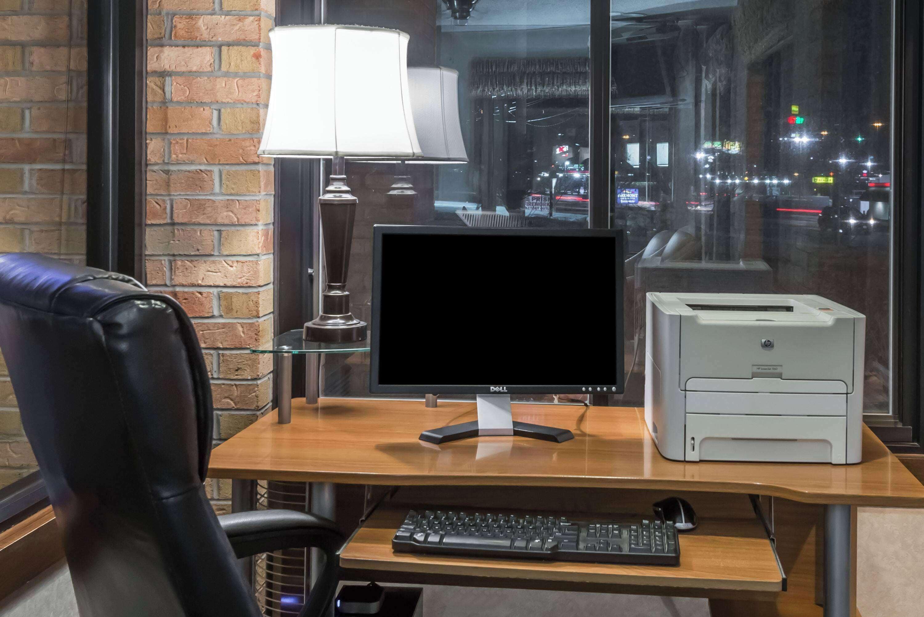 Un escritorio con un monitor de computadora, impresora, teclado y ratón.