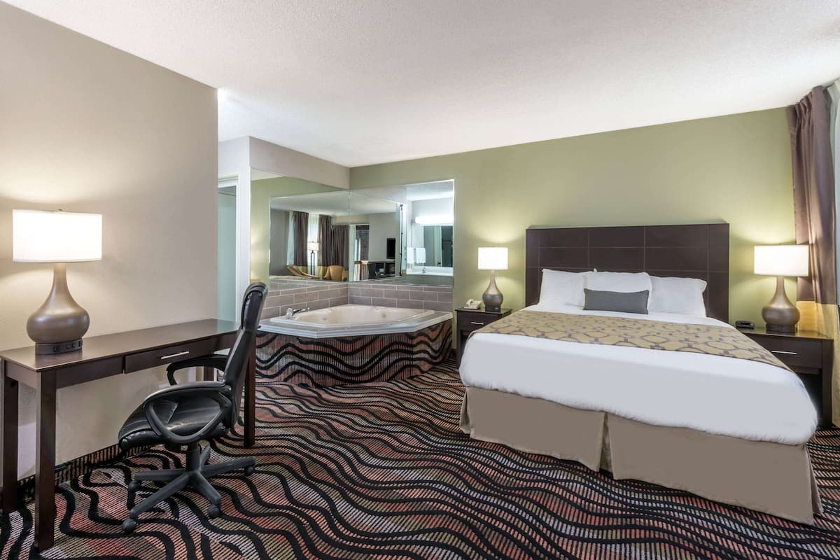 Una habitación de hotel con cama, escritorio, silla, bañera y un espejo grande.
