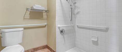 A bathroom with a toilet, a shower with grab bars, and a towel rack.