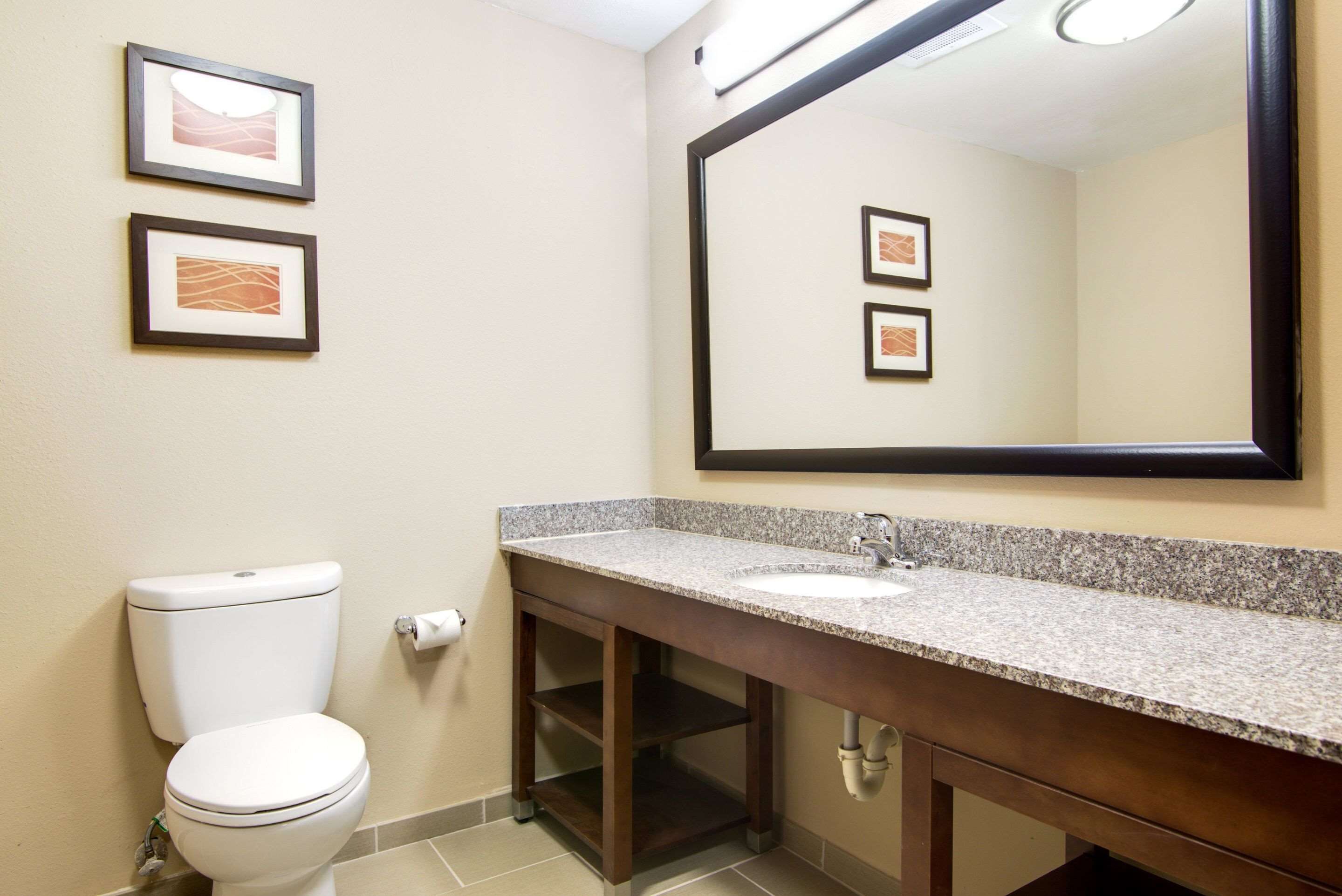 A bathroom with a toilet, sink, and two framed pictures on the wall.
