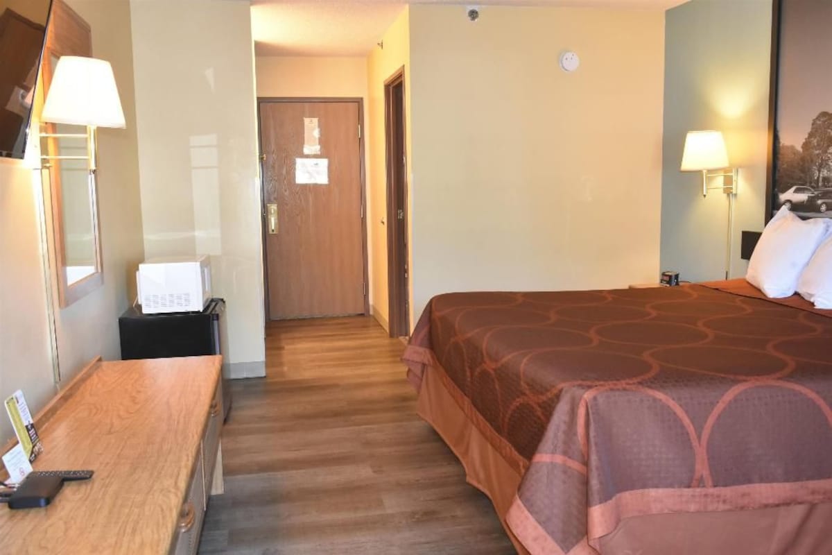Una habitación de hotel con una cama, un escritorio y una lámpara.