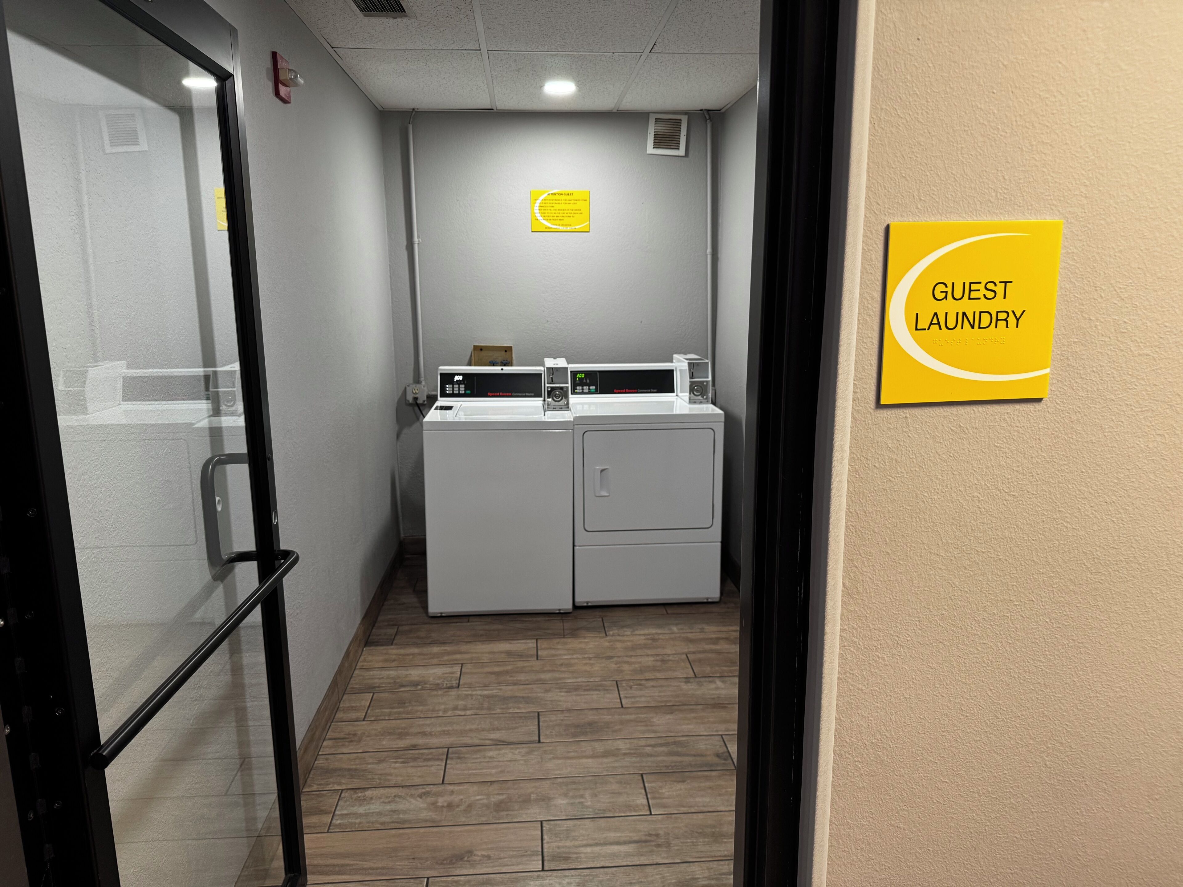 Un espace dédié à la buanderie, avec un panneau indiquant qu’il est réservé aux clients, ainsi qu’une machine à laver et un sèche-linge.