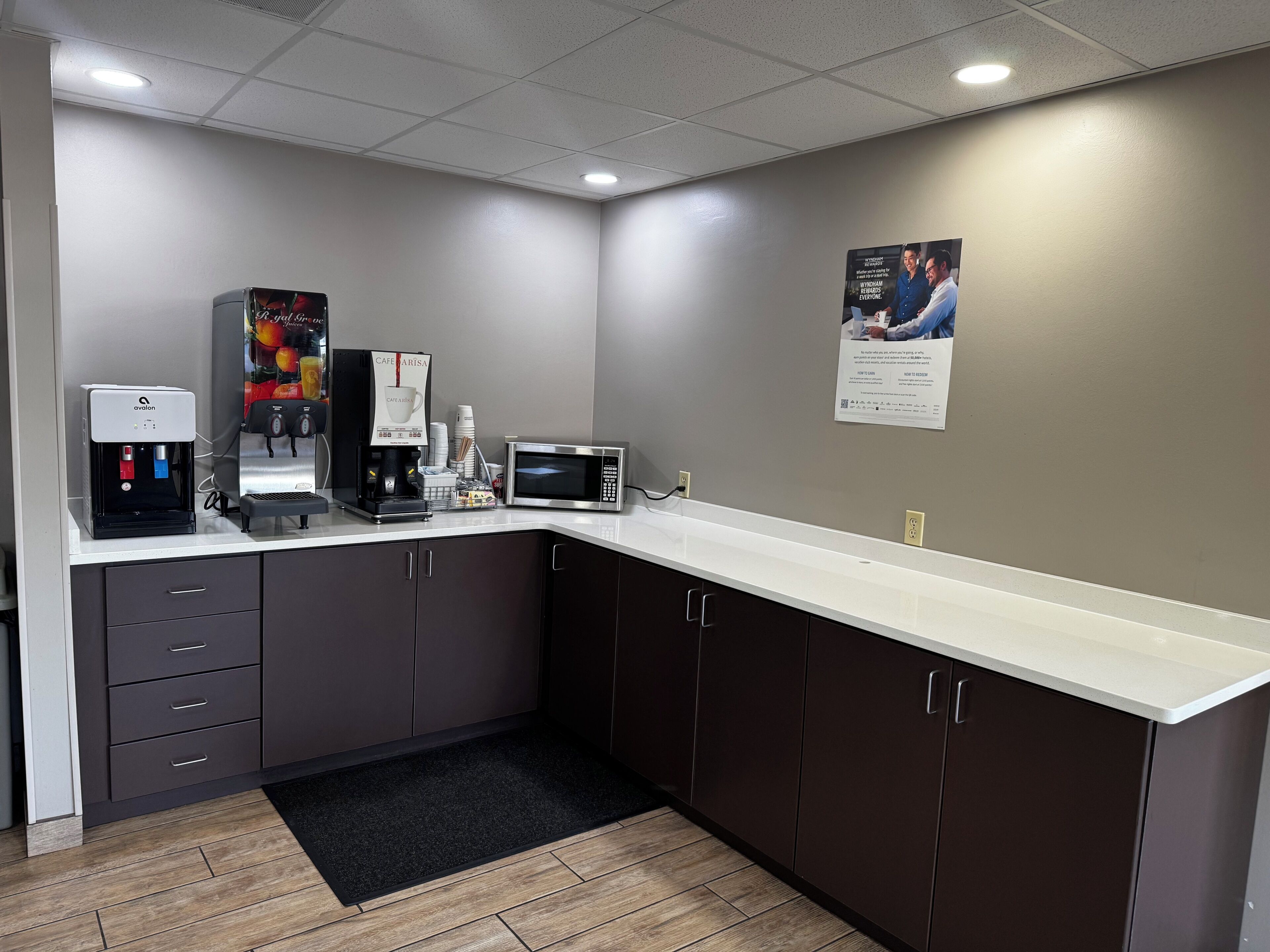 A kitchenette with an espresso machine, coffee maker, microwave, and cabinets.