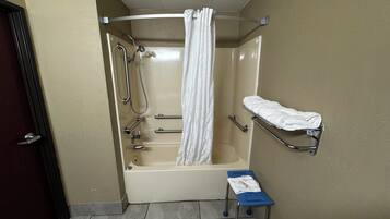 Un baño con bañera, ducha, toallero y un pequeño taburete.