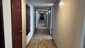 A long, narrow hallway with wooden flooring, doors on both sides, and overhead lighting. - Super 8 by Wyndham Conway (Conway)