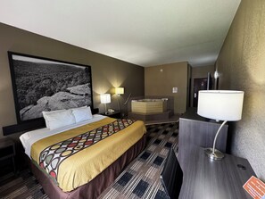 A hotel room with a bed, a large framed picture, a bathtub, and a desk with a lamp. - Super 8 by Wyndham Conway (Conway)