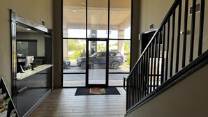 A reception area with a desk, a black staircase, and a view of parked cars outside. - Super 8 by Wyndham Conway (Conway)