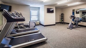 Ein Fitnessraum mit Laufbändern, einem Ergometer und einem Gewichtständer.