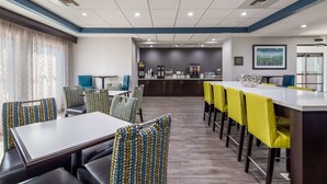 Ein moderner Hotel-Speiseraum mit einer langen Theke, mehreren Tischen und Stühlen.