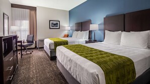 Ein Hotelzimmer mit zwei Betten, einem Schreibtisch mit Stuhl, einem Fernseher und einem Bild an der Wand.
