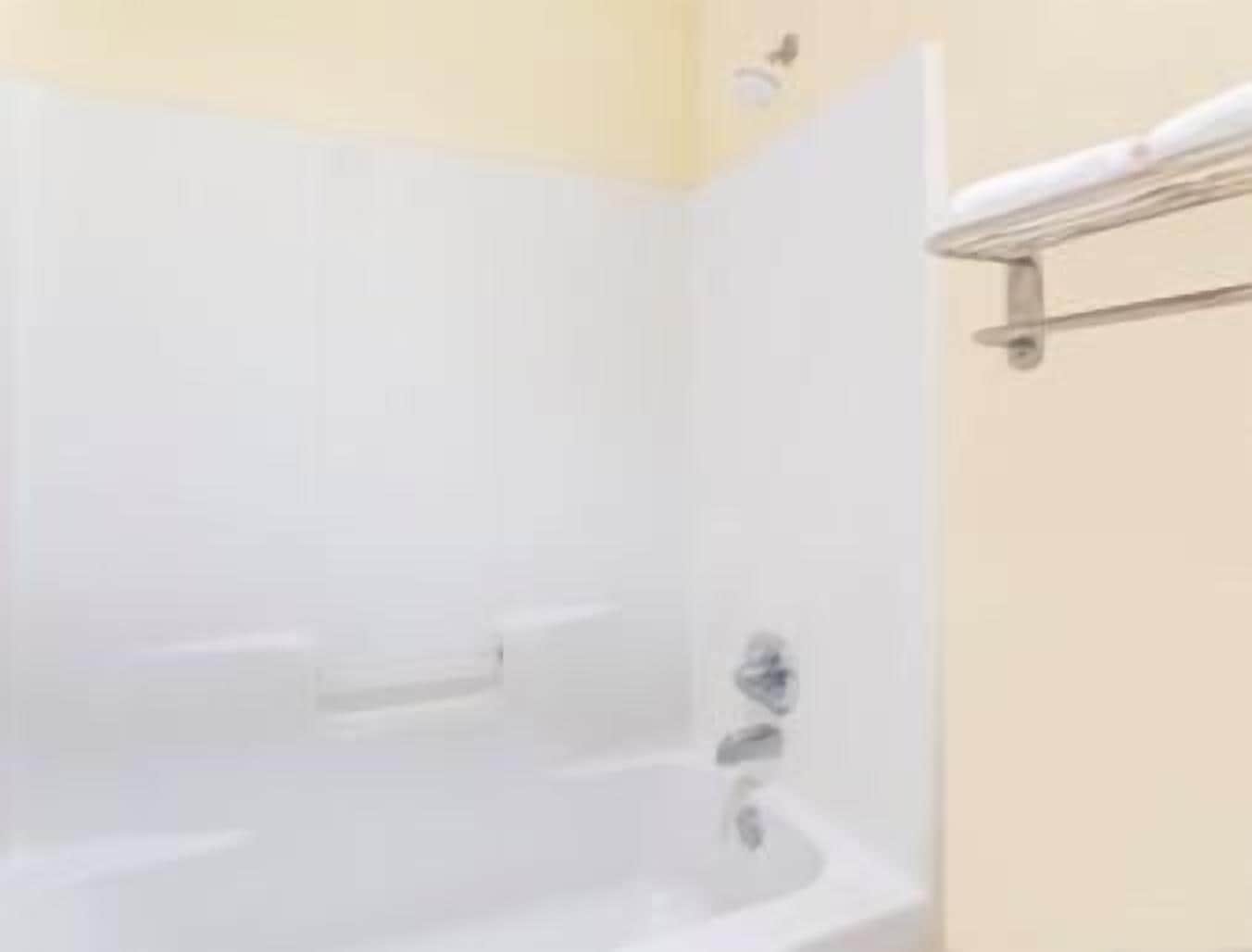 Bagno con vasca da bagno bianca, zona doccia e porta asciugamani.