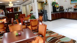 A hotel dining area with wooden tables and chairs, a kitchen area with appliances, and a clock on the wall. - Super 8 by Wyndham Dublin (Dublin)