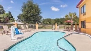 A swimming pool with lounge chairs and umbrellas, surrounded by a fence and trees. - Super 8 by Wyndham Dublin (Dublin)