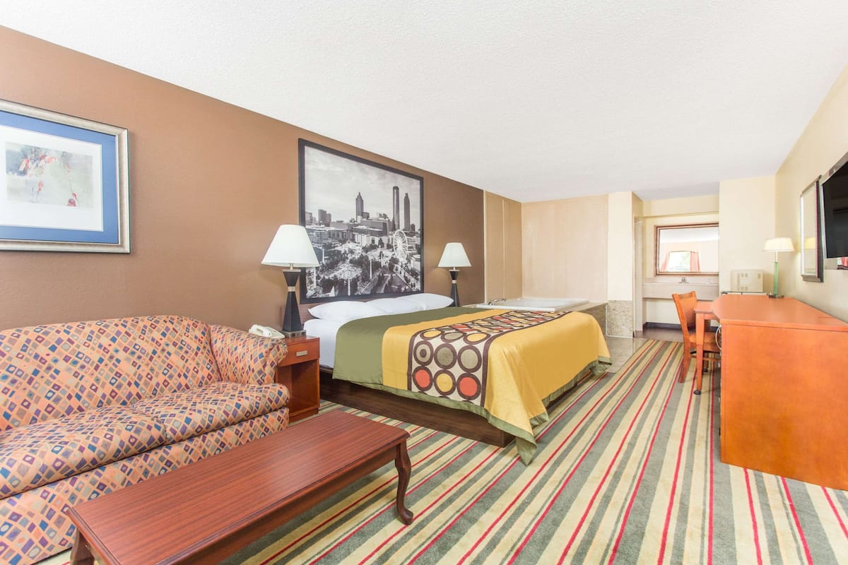Ein Hotelzimmer mit einem Bett, einer Couch, einem Esstisch und einem Stuhl.