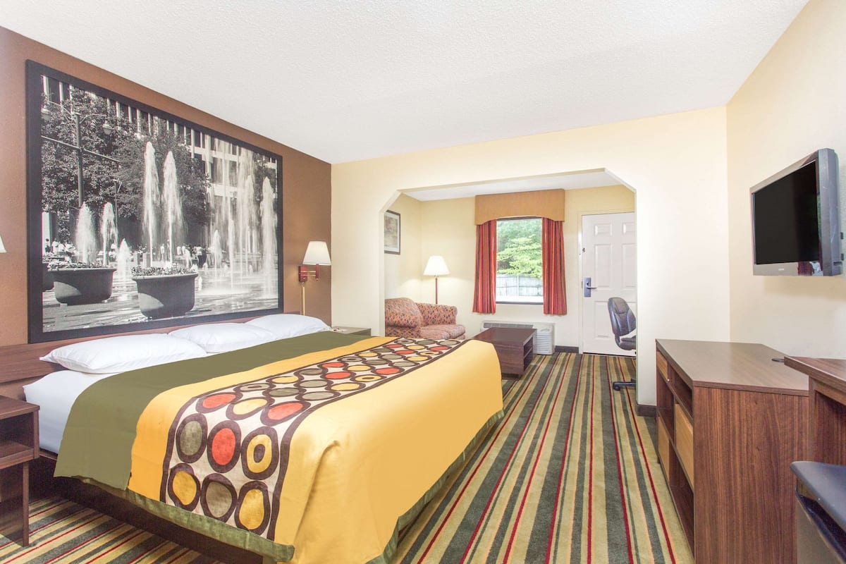 Ein Hotelzimmer mit einem großen Bett, einem Schreibtisch, einem Fernseher und einem Bild einer Springbrunnen.