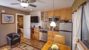 A compact kitchen with wooden cabinets, a microwave, a refrigerator, and a ceiling fan. - Stardust Lodge (South Lake Tahoe)