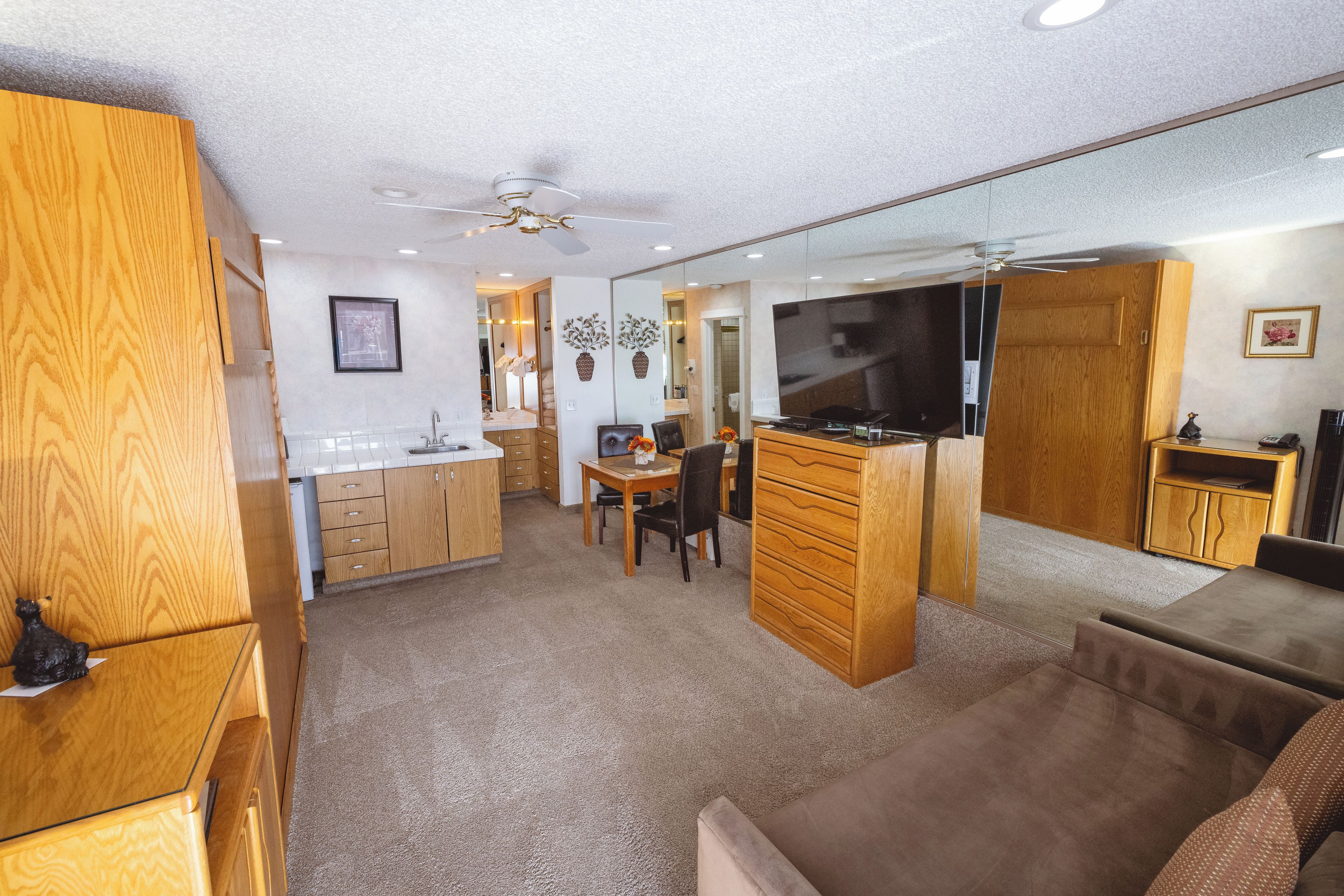 A compact living space with a kitchenette, dining area, and a seating area with a TV.