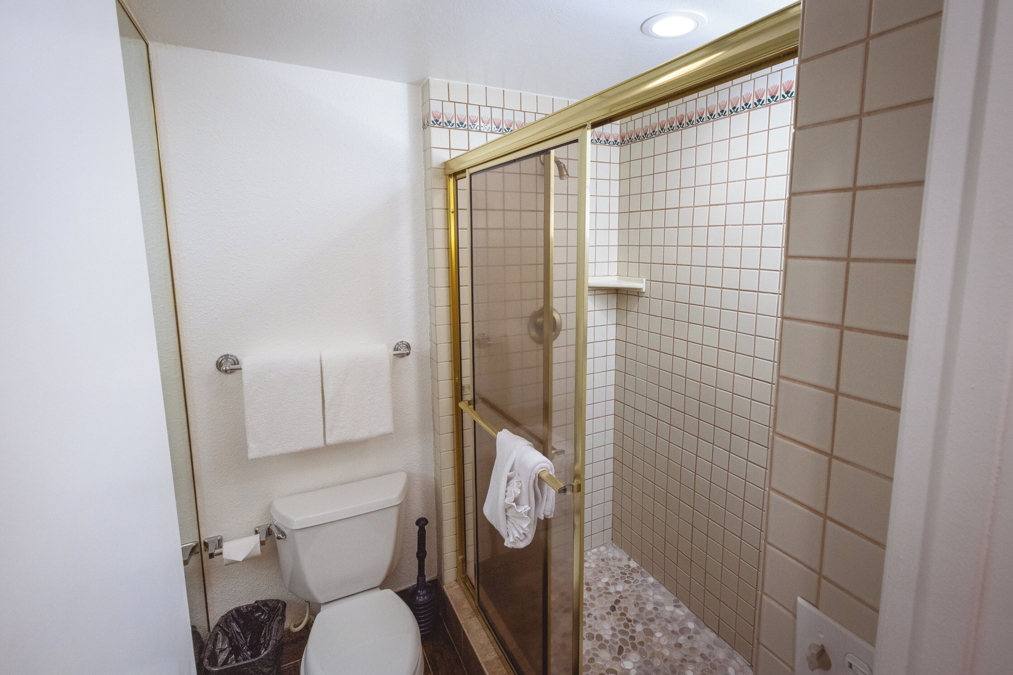 Une salle de bain avec des toilettes, une douche dotée d’une porte en verre et un mur carrelé.