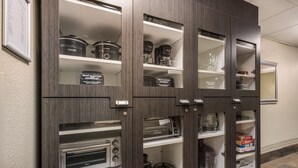 Un meuble de cuisine doté de plusieurs étagères, contenant des appareils de cuisine et des récipients de rangement.