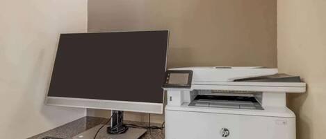A desktop computer with a monitor, keyboard, and mouse on a granite countertop, next to an HP printer.