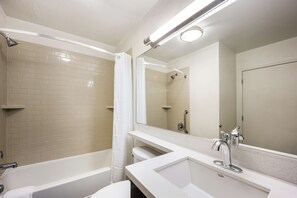 Ein modernes Badezimmer mit einer Badewanne, einer Dusche, einem Waschbecken und einem Spiegel.