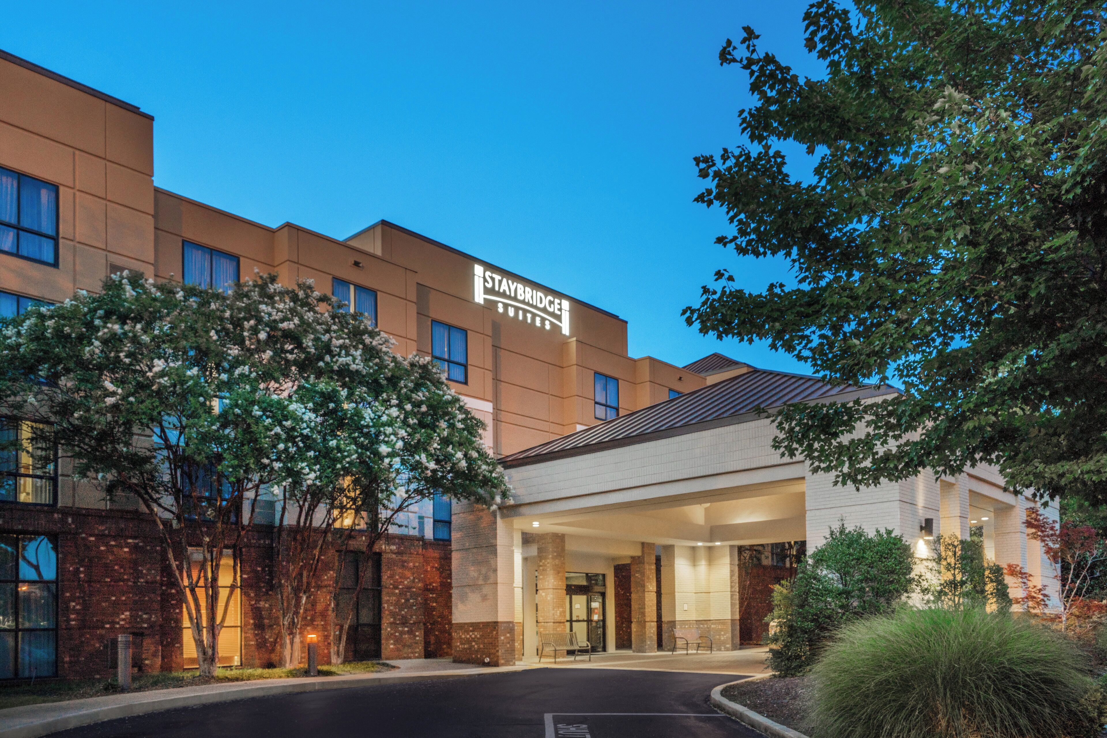 Un hotel Staybridge Suites con fachada moderna, entrada cubierta y estacionamiento.