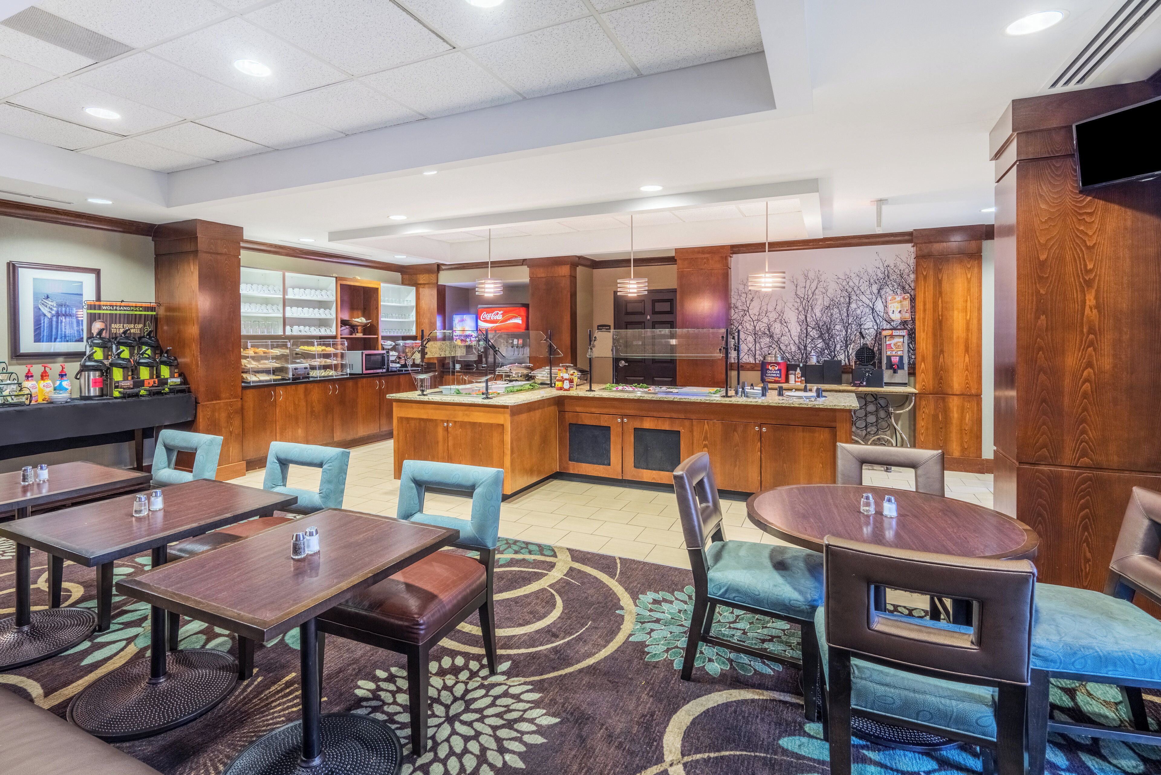 A hotel lobby with a bar area, seating arrangements, and a large television screen.