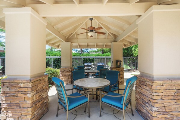 An outdoor patio with a round table and blue chairs, surrounded by stone pillars, under a ceiling fan. - Staybridge Suites Memphis - Poplar Ave East by IHG (Memphis)