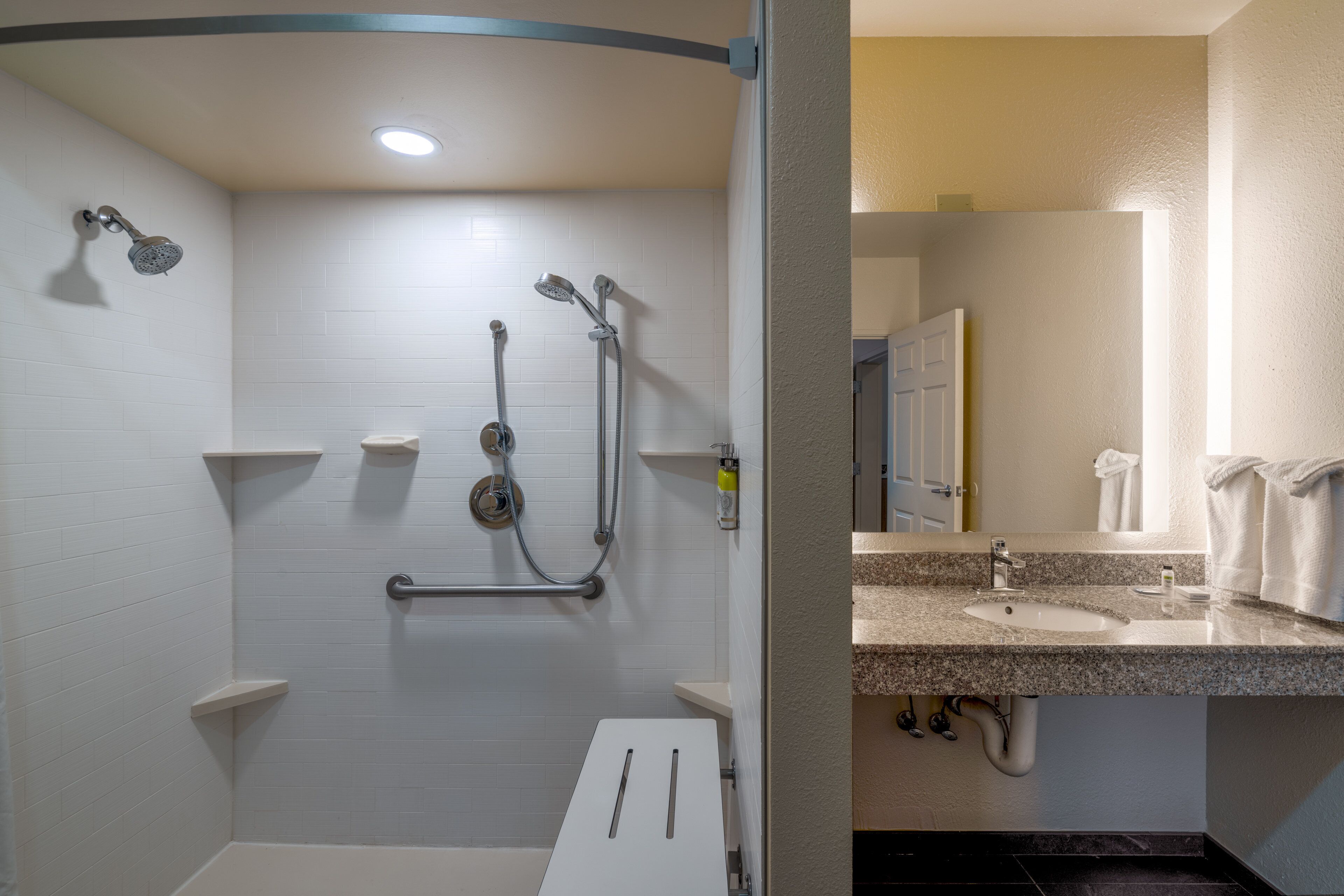 A bathroom with a shower, a sink, and a mirror.