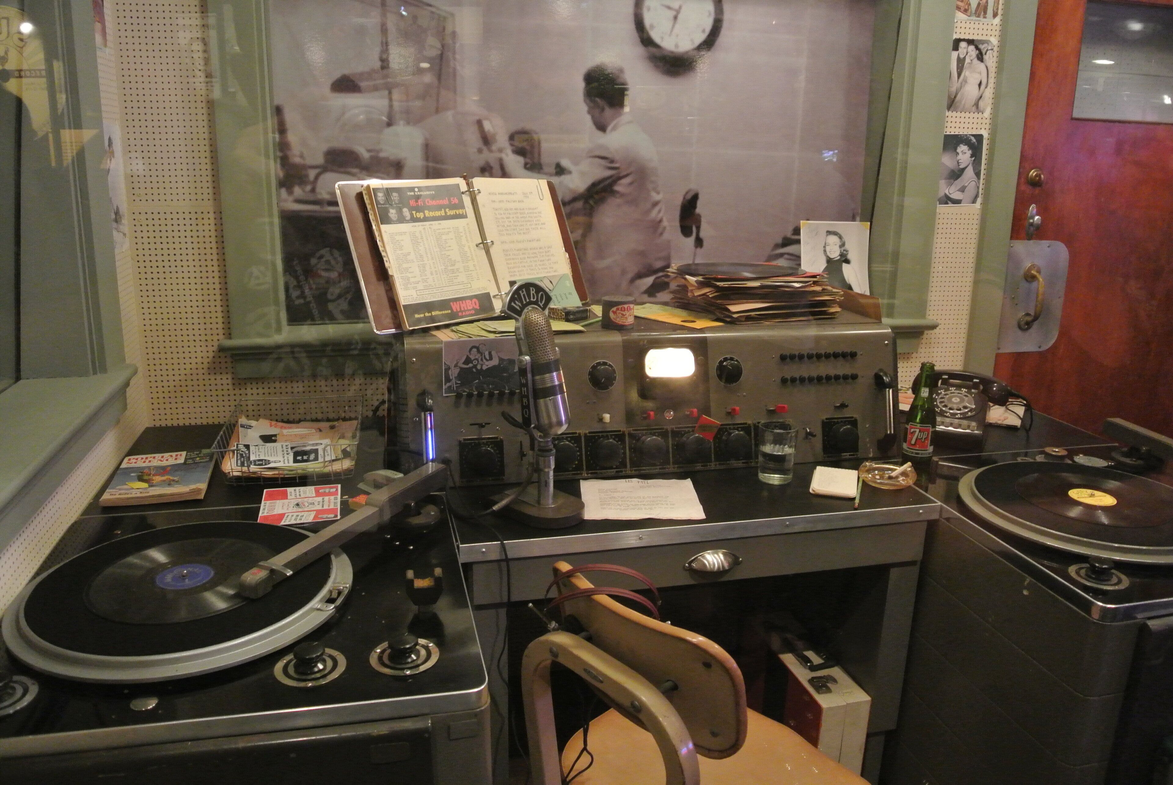 A vintage radio station setup with two turntables, a microphone, and various equipment.