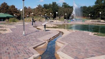 A park with a fountain, brick pathways, and informational signs.