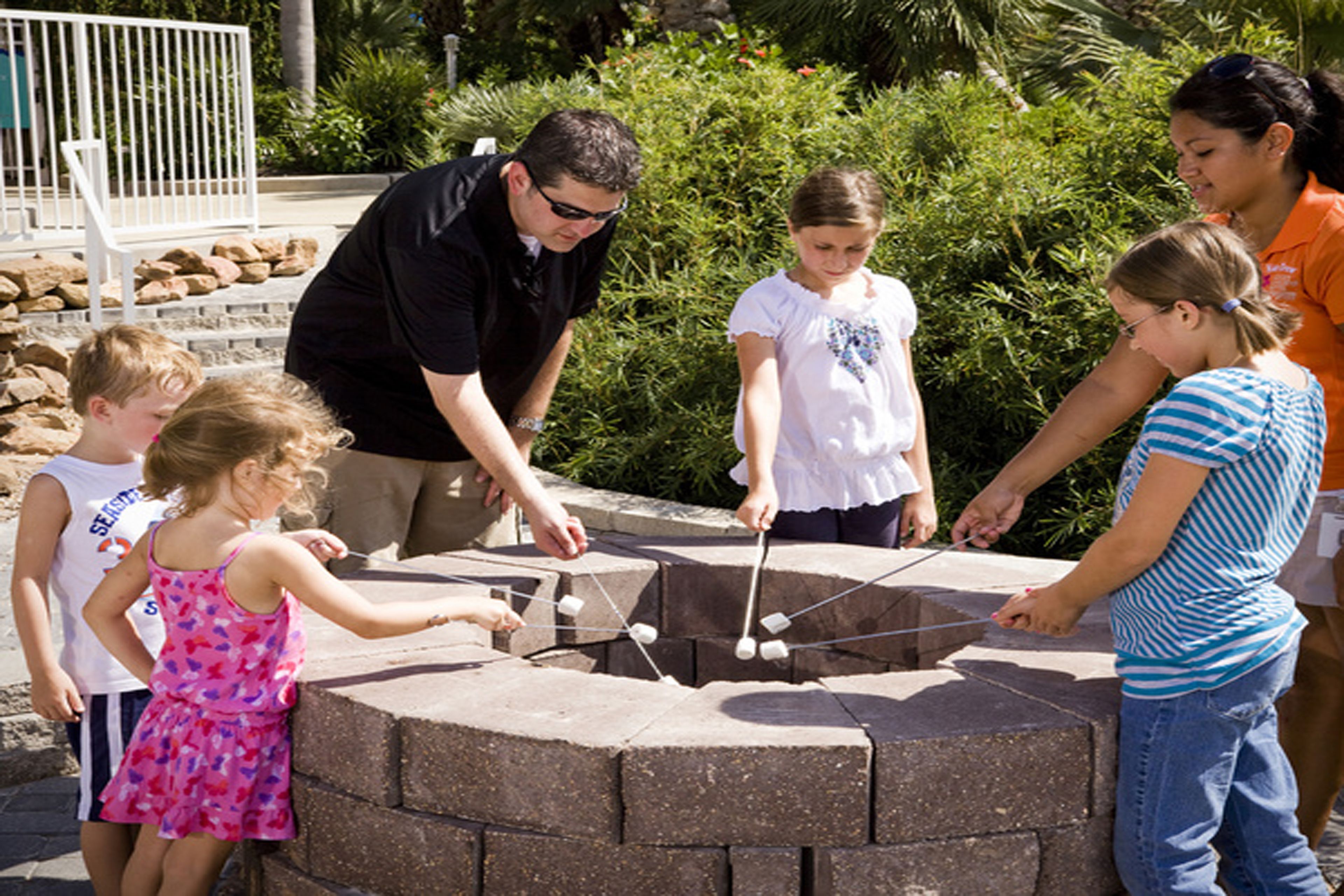 A group of people around a stone outdoor cooking structure.