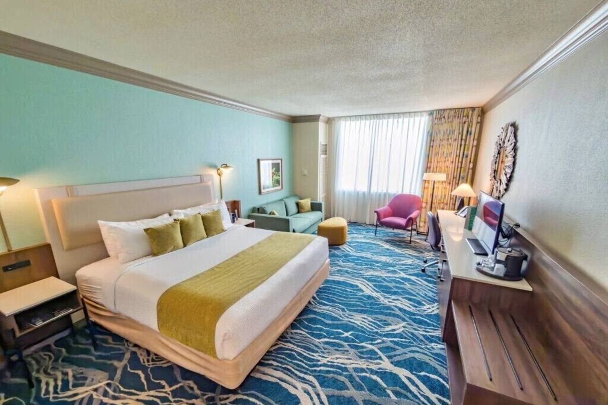 Une chambre d’hôtel avec un grand lit, un bureau, une chaise et un téléviseur.