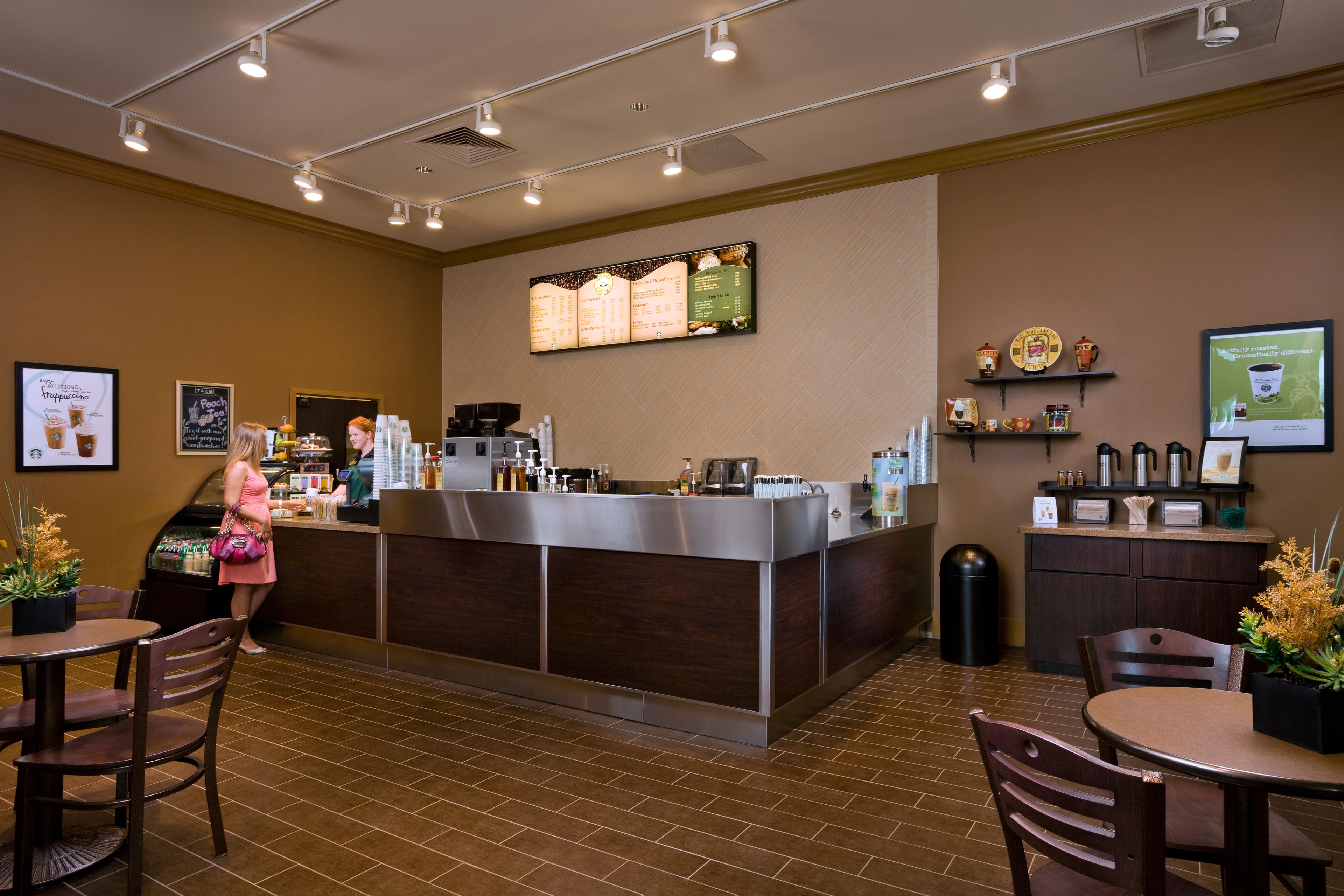 A restaurant with a counter, seating area, and menu board.